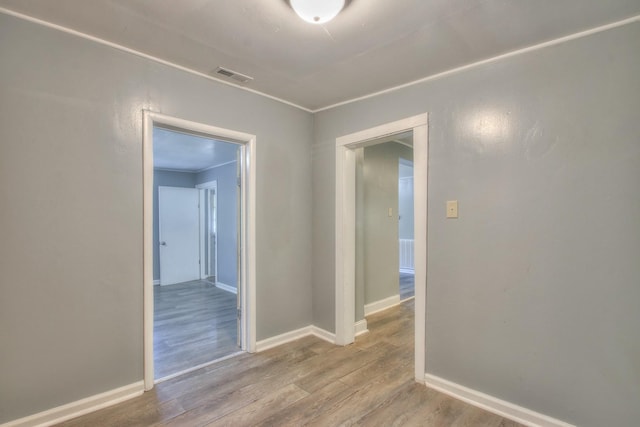 empty room featuring wood finished floors, visible vents, and baseboards