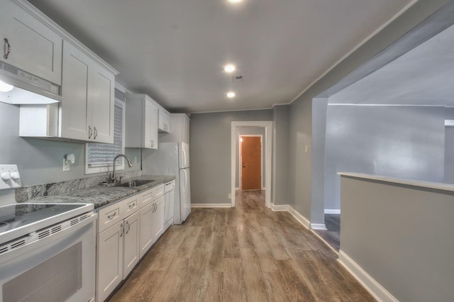 kitchen featuring light stone counters, under cabinet range hood, white appliances, a sink, and white cabinetry