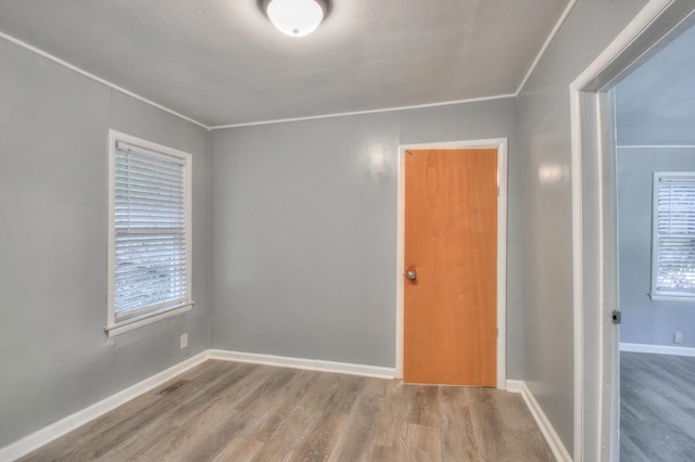 spare room featuring a wealth of natural light, visible vents, baseboards, and wood finished floors