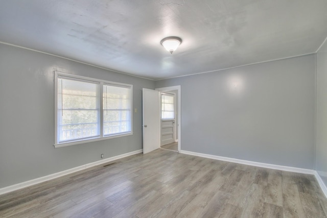 empty room with wood finished floors, visible vents, and baseboards