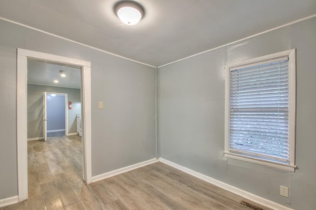 empty room featuring baseboards, visible vents, and wood finished floors