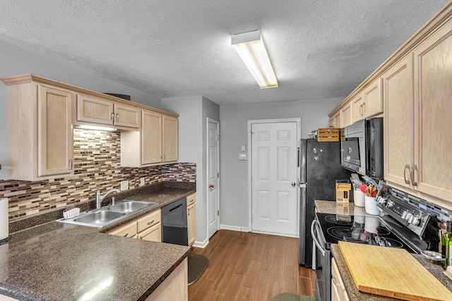 kitchen with light brown cabinets, dark wood-type flooring, a sink, appliances with stainless steel finishes, and dark countertops