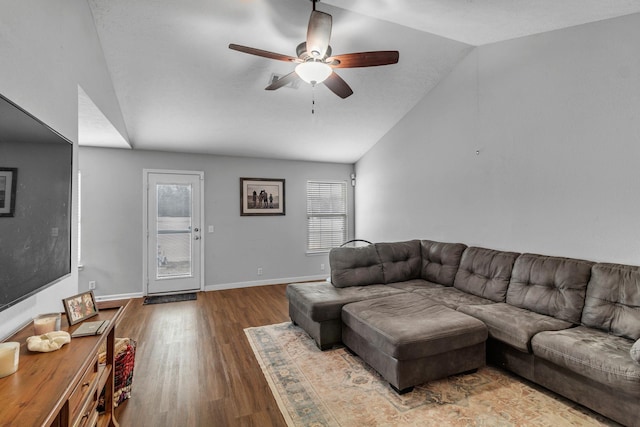 living room with ceiling fan, vaulted ceiling, baseboards, and wood finished floors