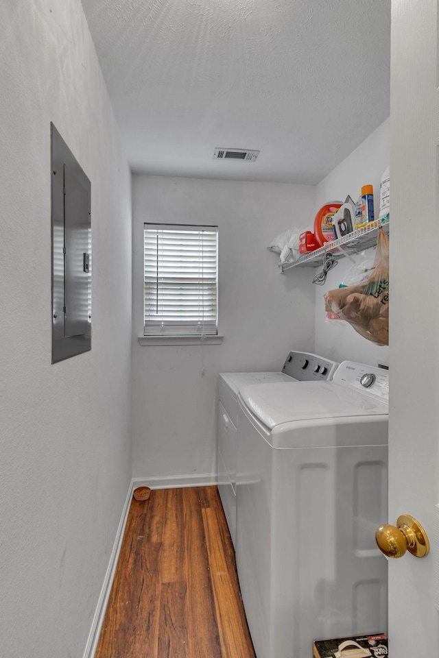 laundry area with laundry area, baseboards, visible vents, washer and clothes dryer, and wood finished floors