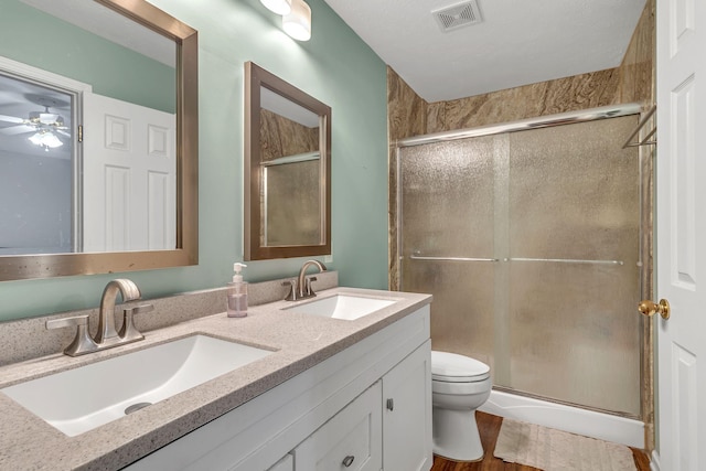 full bathroom with toilet, a shower stall, visible vents, and a sink