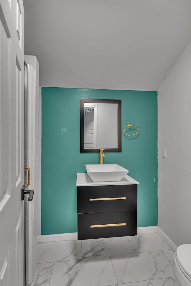 bathroom featuring toilet, marble finish floor, baseboards, and vanity