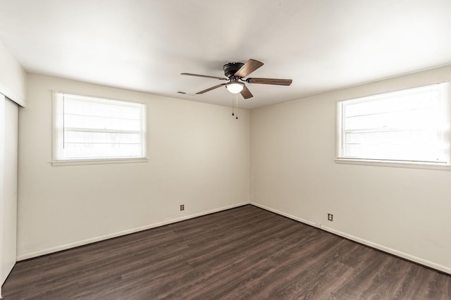 empty room with baseboards, dark wood-style flooring, and a healthy amount of sunlight