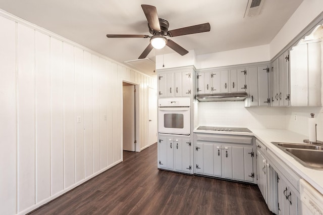 kitchen with light countertops, decorative backsplash, dark wood-type flooring, a sink, and white appliances