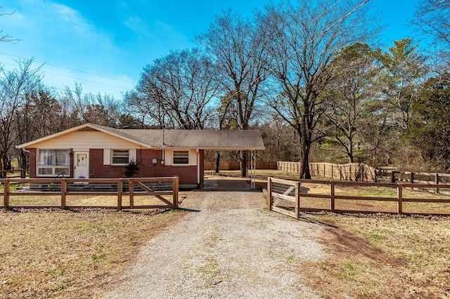 view of front facade with a carport, brick siding, a fenced front yard, and driveway