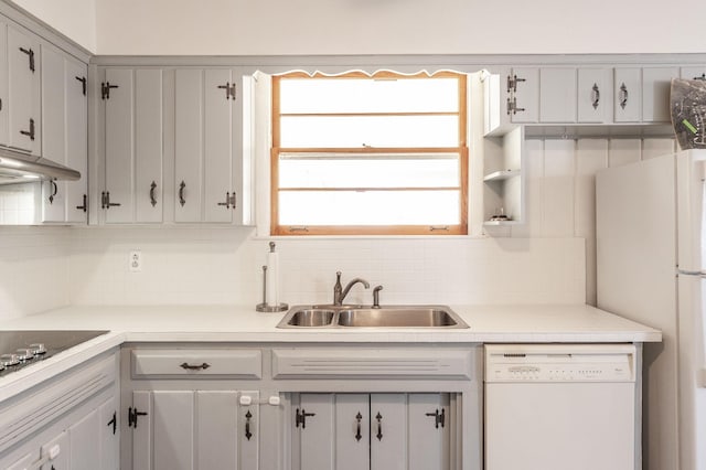 kitchen with white appliances, tasteful backsplash, light countertops, under cabinet range hood, and a sink