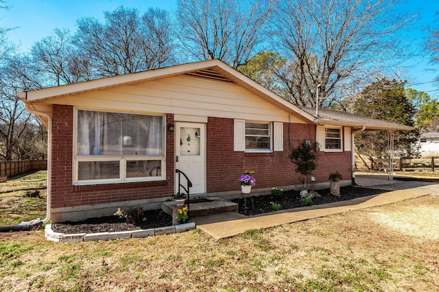 view of front of home featuring entry steps, brick siding, fence, and a front yard