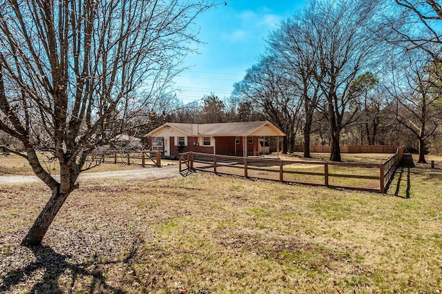 exterior space featuring dirt driveway, fence, and a front lawn