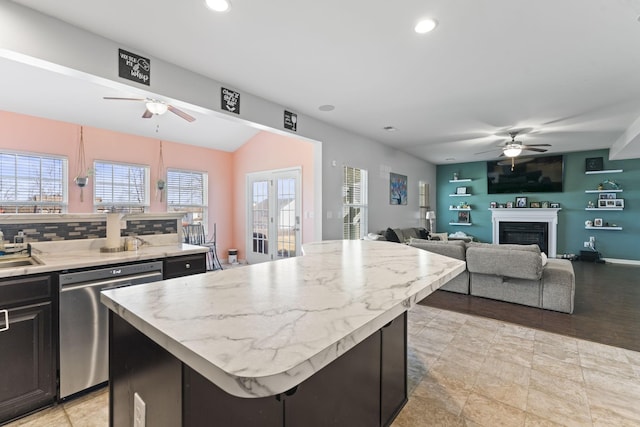 kitchen featuring a center island, a fireplace, light countertops, backsplash, and dishwasher