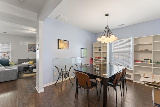 dining room with a chandelier, wood-type flooring, visible vents, and baseboards