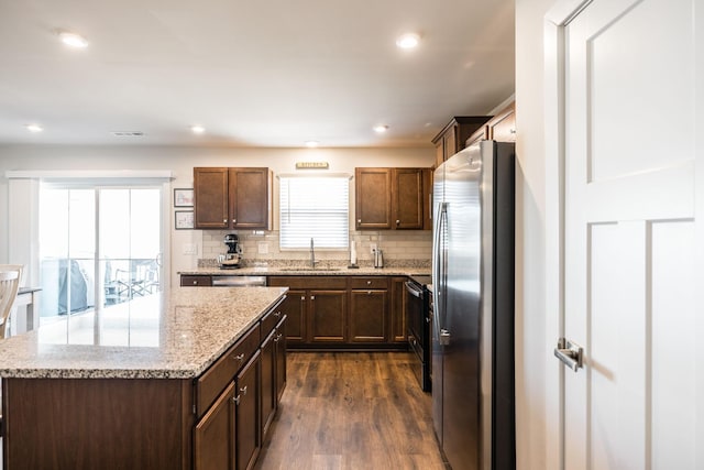 kitchen with a center island, dark wood finished floors, backsplash, appliances with stainless steel finishes, and a sink