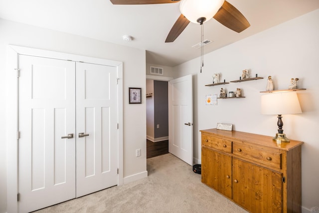 bedroom featuring a ceiling fan, a closet, visible vents, and light colored carpet