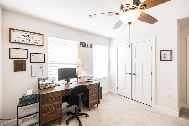 office space featuring light colored carpet, ceiling fan, and baseboards