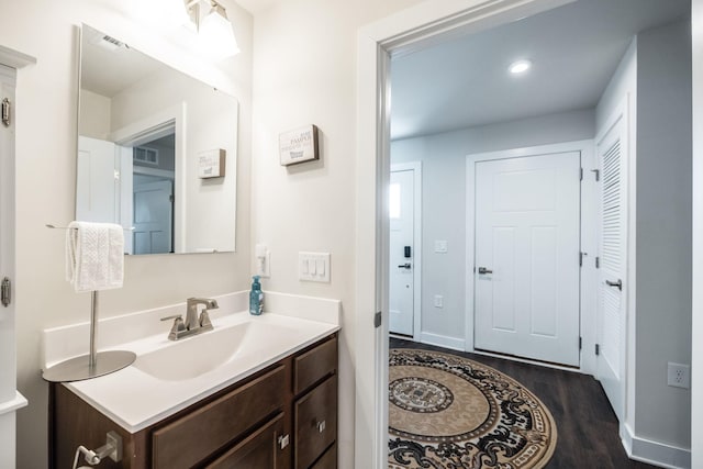 bathroom featuring baseboards, visible vents, wood finished floors, and vanity