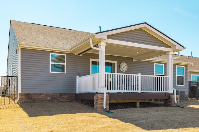 view of front of property featuring a shingled roof, a porch, and cooling unit