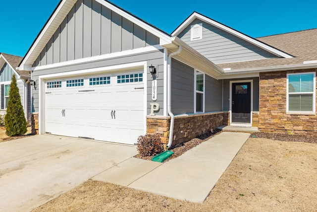 view of front of home with a shingled roof, concrete driveway, an attached garage, board and batten siding, and stone siding