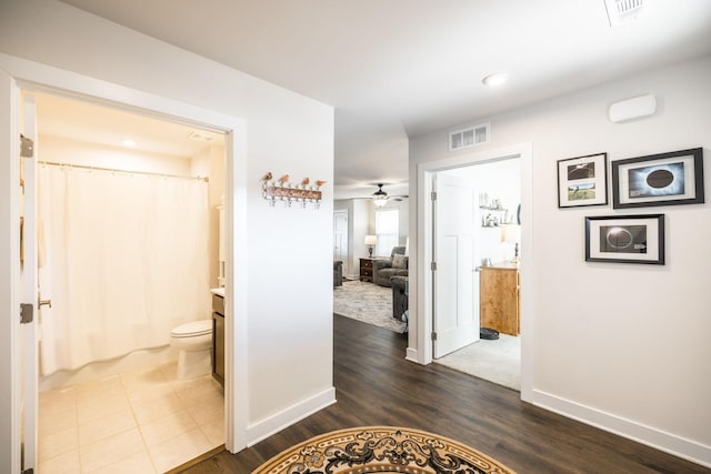 corridor featuring dark wood finished floors, visible vents, and baseboards