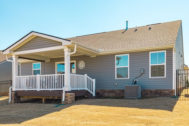 rear view of property with covered porch, central AC, roof with shingles, and a lawn