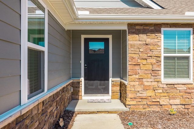 property entrance featuring stone siding and roof with shingles