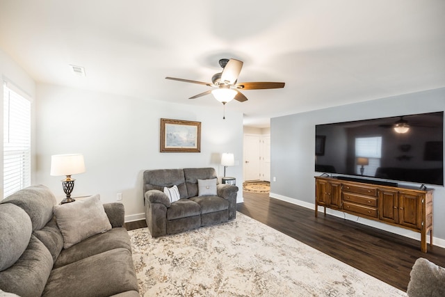 living area with visible vents, dark wood-type flooring, a ceiling fan, and baseboards