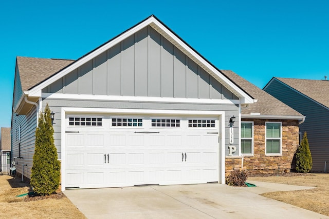 view of front facade with a shingled roof, concrete driveway, an attached garage, board and batten siding, and stone siding