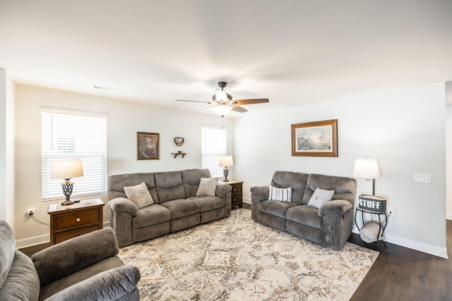 living room featuring ceiling fan, visible vents, baseboards, and wood finished floors