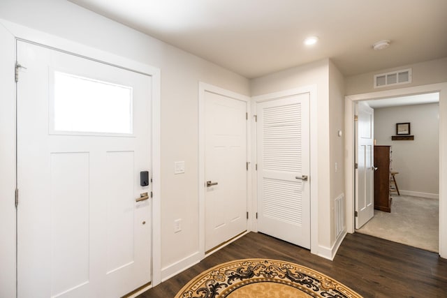 foyer with dark wood finished floors, visible vents, and baseboards