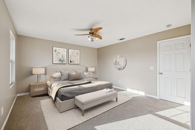 bedroom with light carpet, ceiling fan, visible vents, and baseboards