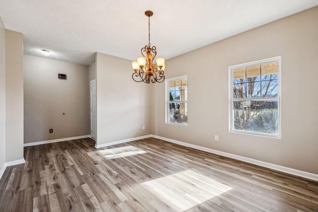 unfurnished dining area with wood finished floors, a wealth of natural light, and baseboards