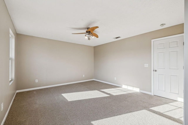 carpeted empty room featuring baseboards, visible vents, and a ceiling fan