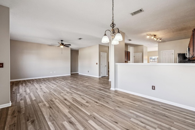 unfurnished living room with ceiling fan, wood finished floors, visible vents, and baseboards