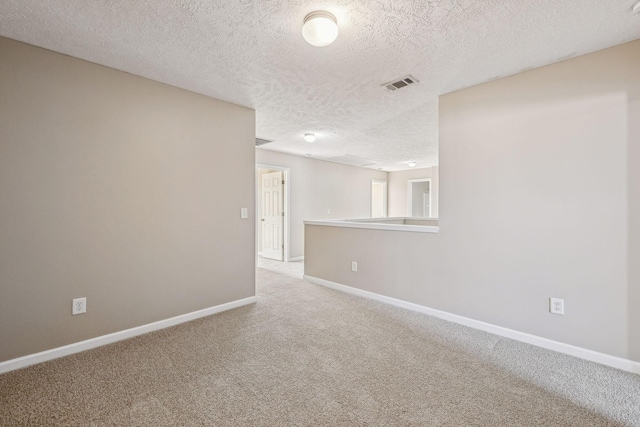 empty room with carpet, visible vents, a textured ceiling, and baseboards