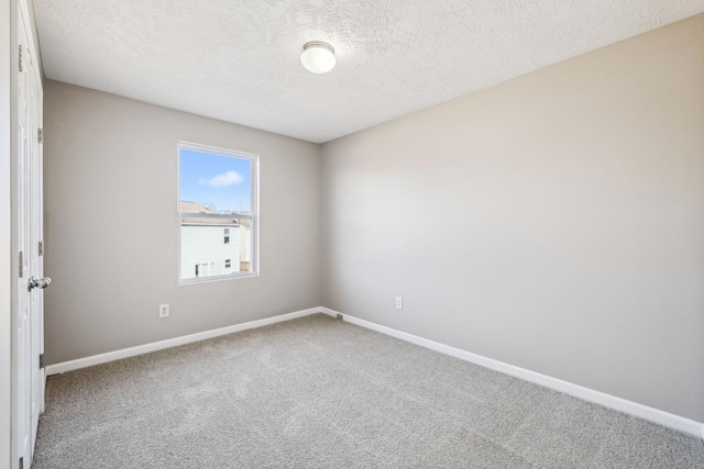 spare room featuring carpet floors, a textured ceiling, and baseboards