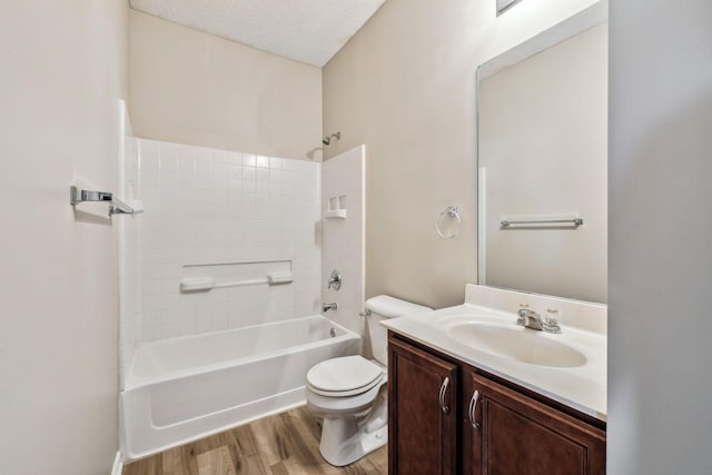 bathroom with toilet, wood finished floors, bathtub / shower combination, a textured ceiling, and vanity