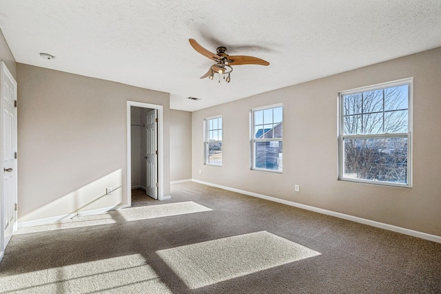 unfurnished bedroom with a textured ceiling, carpet floors, and baseboards