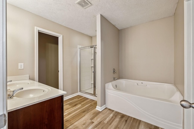 full bathroom with visible vents, a bath, wood finished floors, a shower stall, and a sink