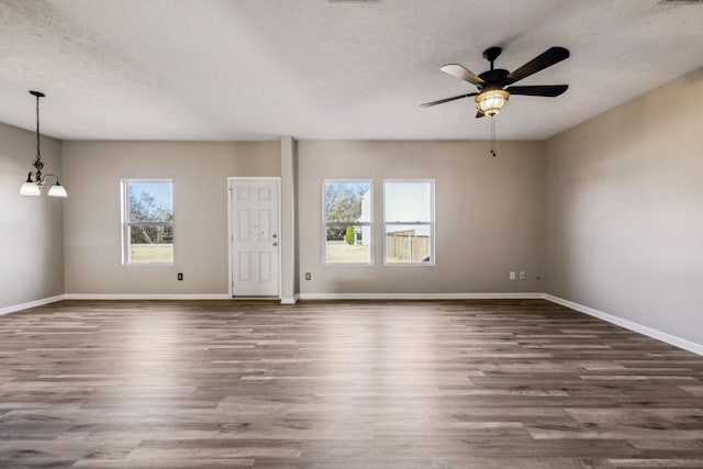 interior space with dark wood finished floors, a textured ceiling, baseboards, and ceiling fan with notable chandelier