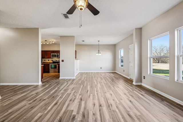 unfurnished living room with baseboards, visible vents, ceiling fan, a textured ceiling, and light wood-style floors