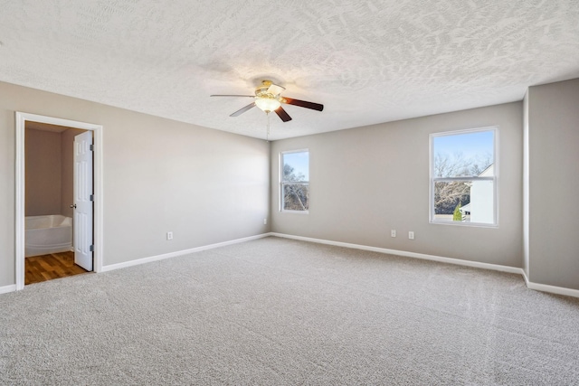 carpeted spare room featuring a textured ceiling, a ceiling fan, and baseboards