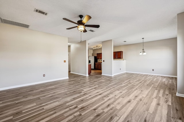 unfurnished living room with ceiling fan, wood finished floors, visible vents, and baseboards