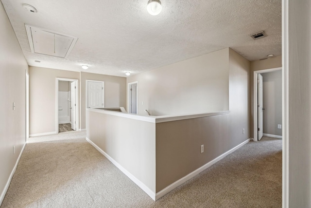 corridor featuring visible vents, carpet, an upstairs landing, and attic access