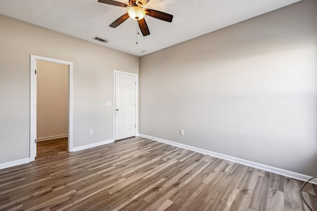 spare room with a ceiling fan, baseboards, visible vents, and wood finished floors