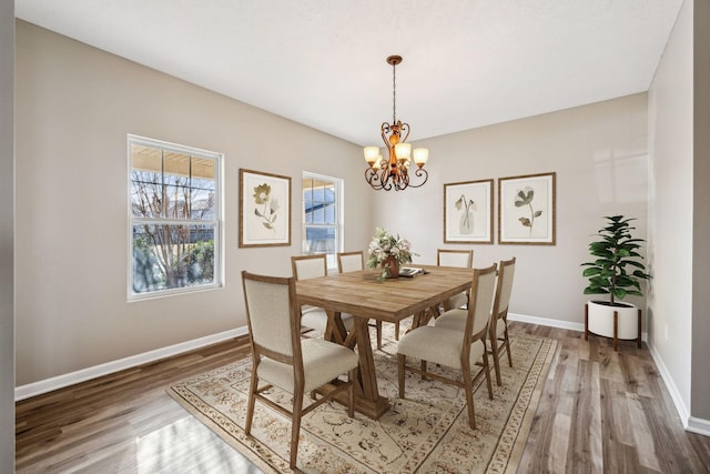 dining area featuring a notable chandelier, baseboards, and wood finished floors