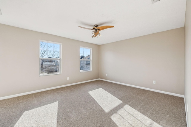 carpeted spare room with a ceiling fan and baseboards