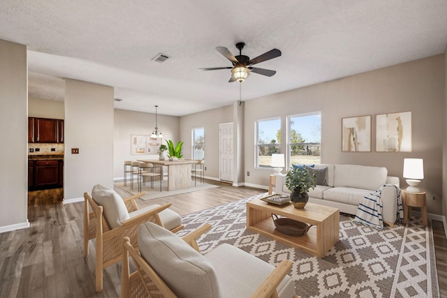 living area featuring ceiling fan, wood finished floors, visible vents, and baseboards