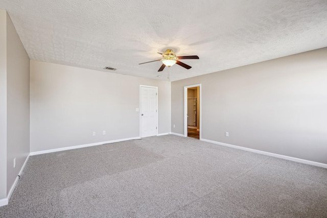 carpeted spare room featuring a ceiling fan, visible vents, a textured ceiling, and baseboards